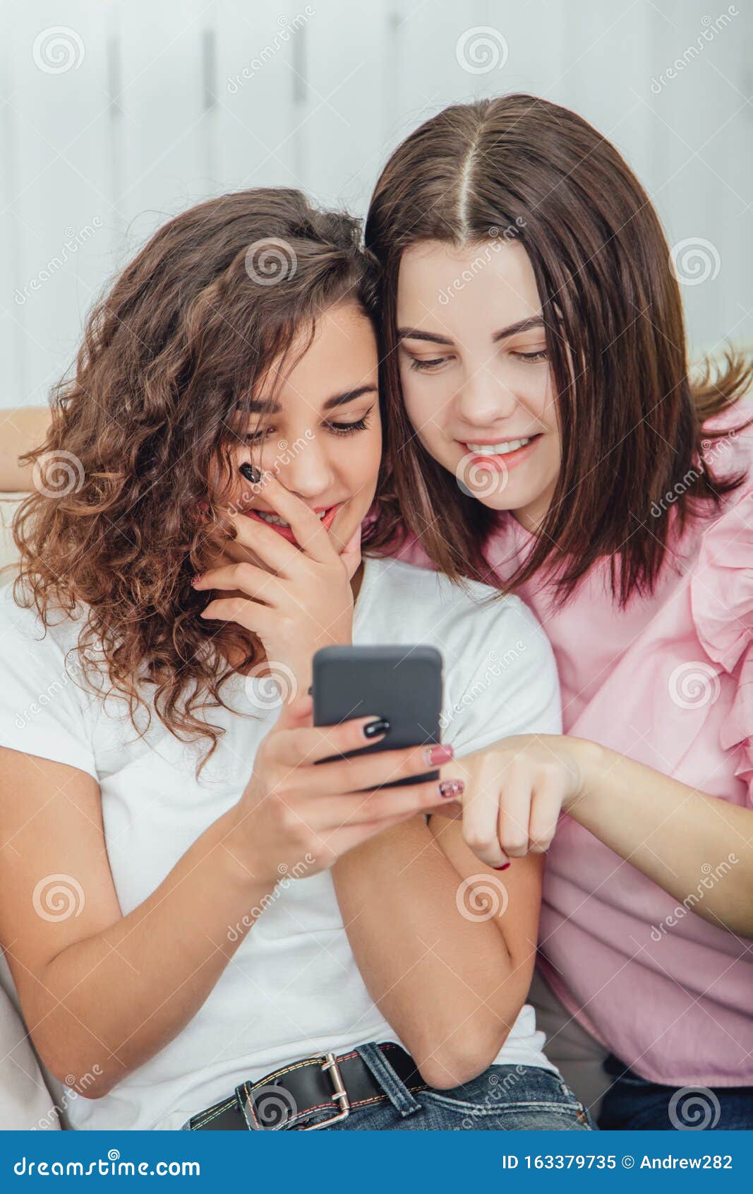 Beautiful Young Girls Sitting on the Sofa, at Home, Looking at the ...