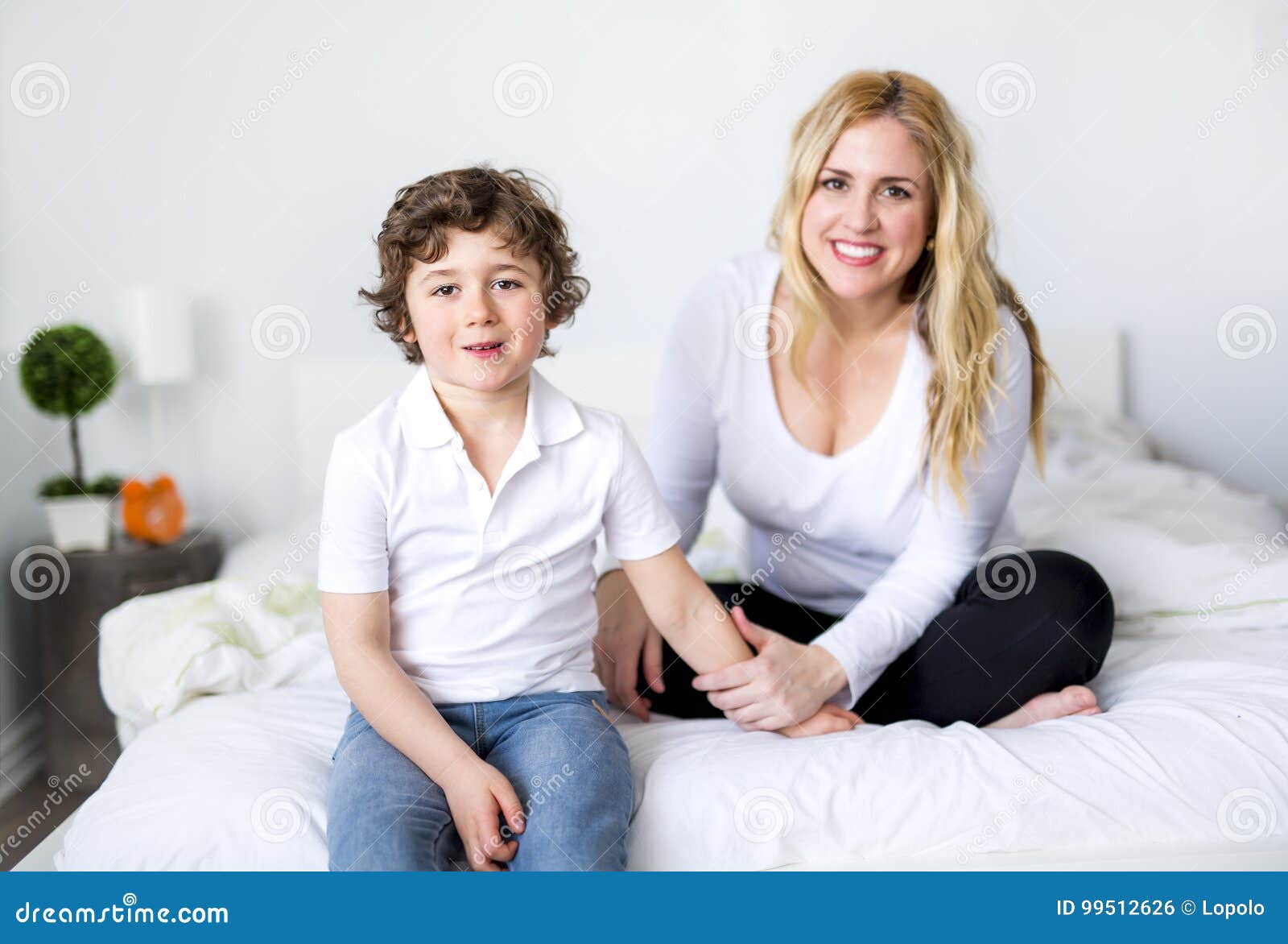 Beautiful Young Mother and Son Lying Together on a Bed Stock Photo