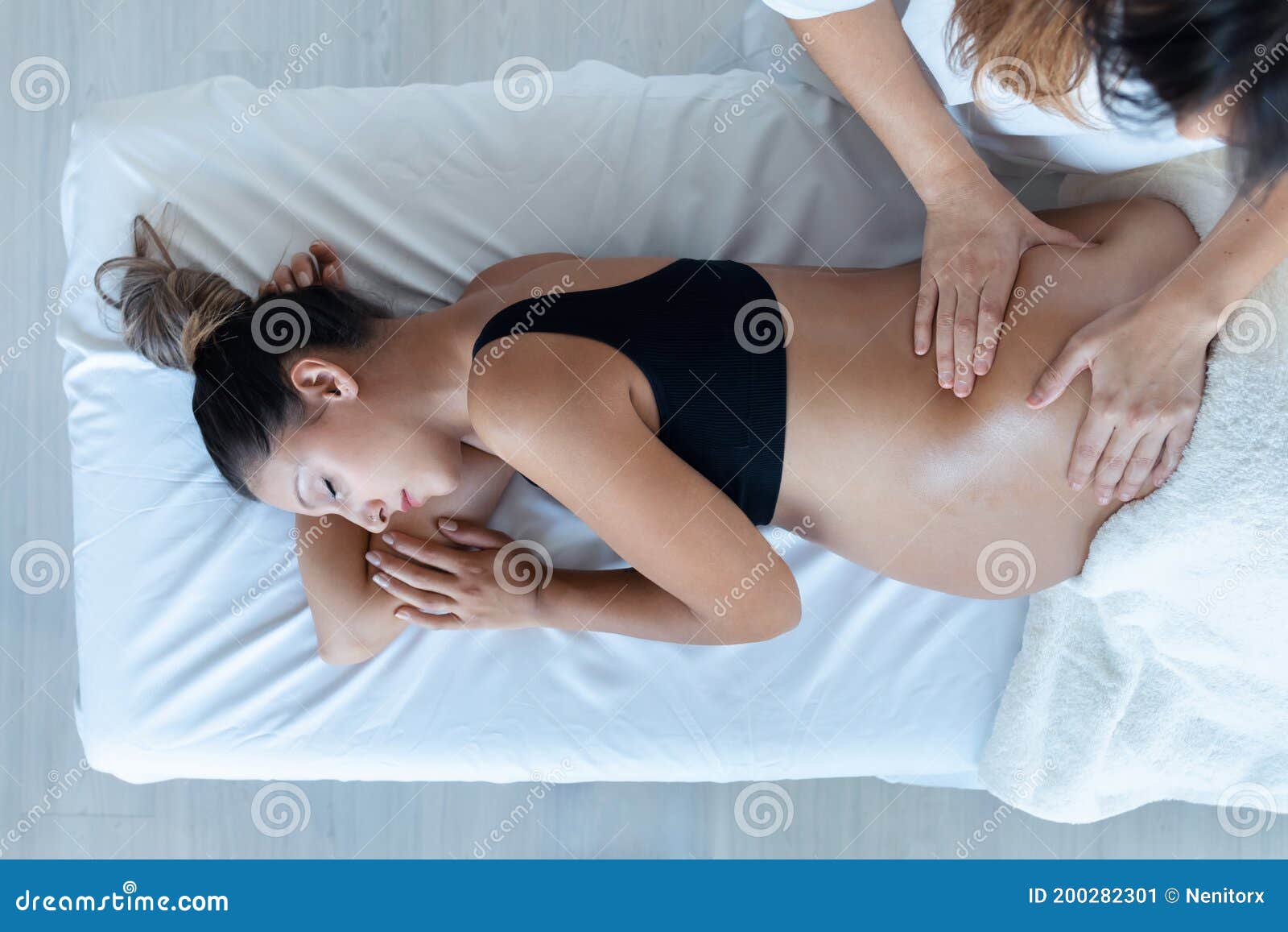 beautiful young physiotherapist woman massaging tummy on pregnant woman on a stretcher at home