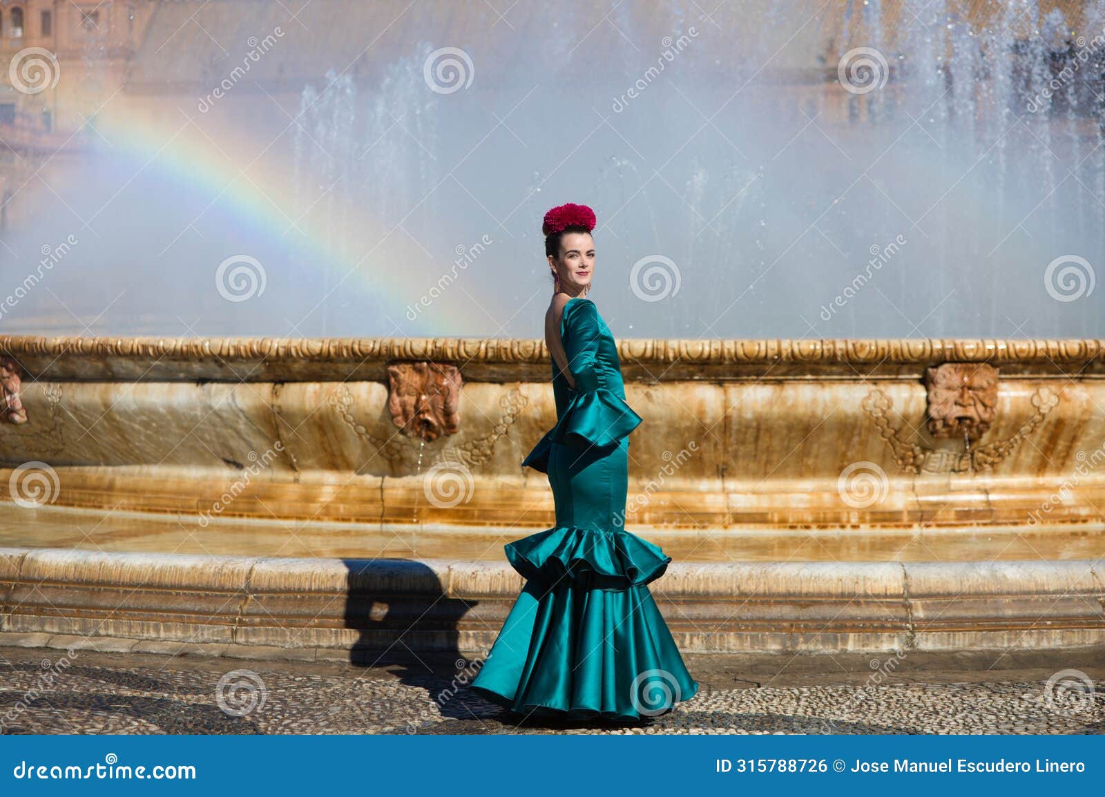 beautiful young woman in a green frilly suit with a flower on her head. the woman is dancing flamenco and is in the most famous