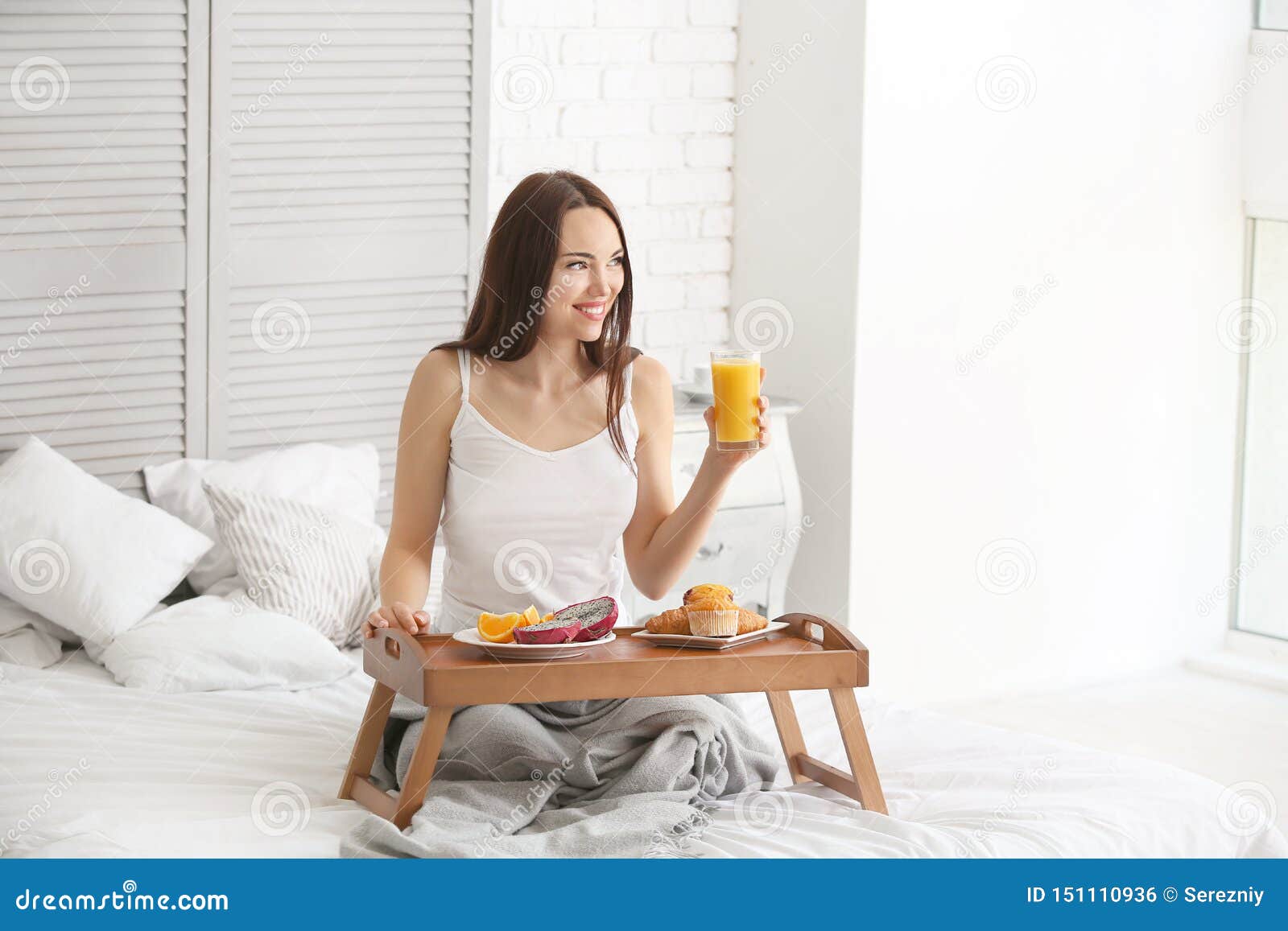beautiful young woman having breakfast on bed at home