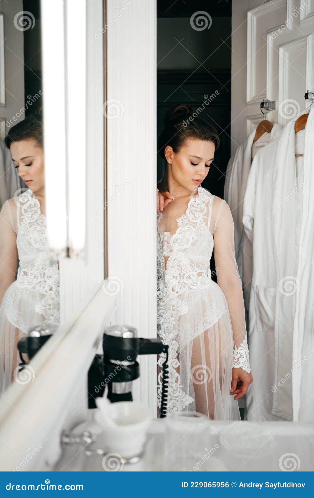 A Beautiful Young Woman in a Lace Robe at the Bathroom Door Stock