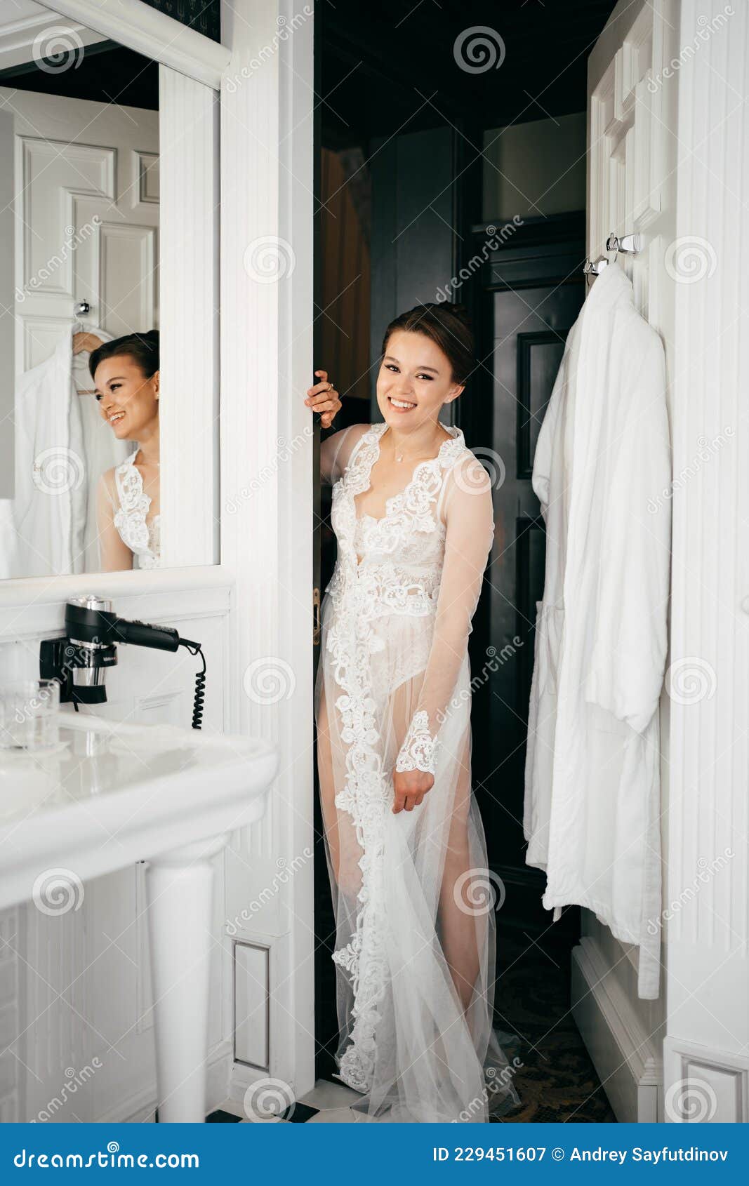 A Beautiful Young Woman in a Lace Robe at the Bathroom Door Stock