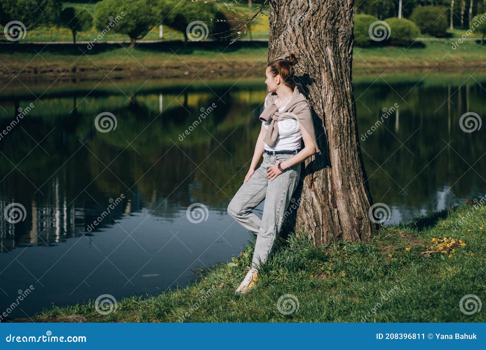 beautiful young woman lying on a field, green grass and dandelion flowers. outdoors enjoy nature. healthy smiling girl lying in