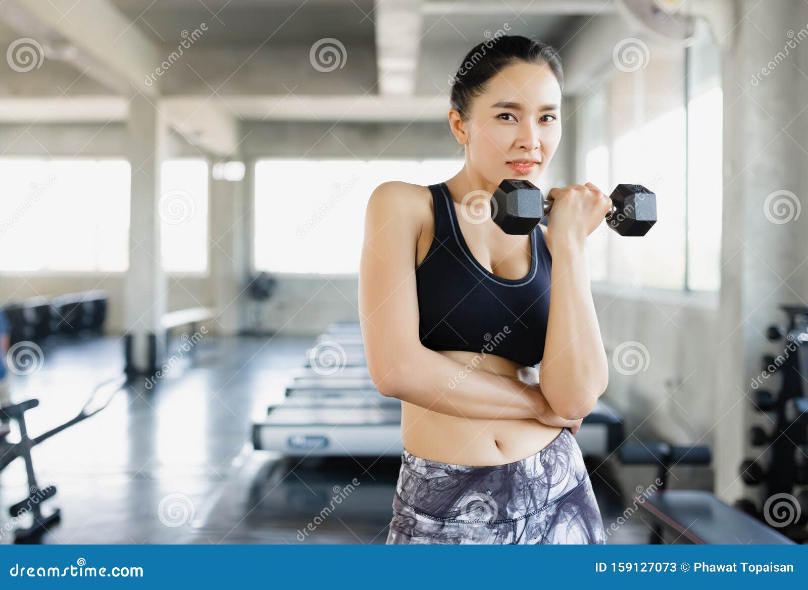 Posing with dumbbell. Beautiful woman with sport body type is in the gym  Stock Photo by mstandret