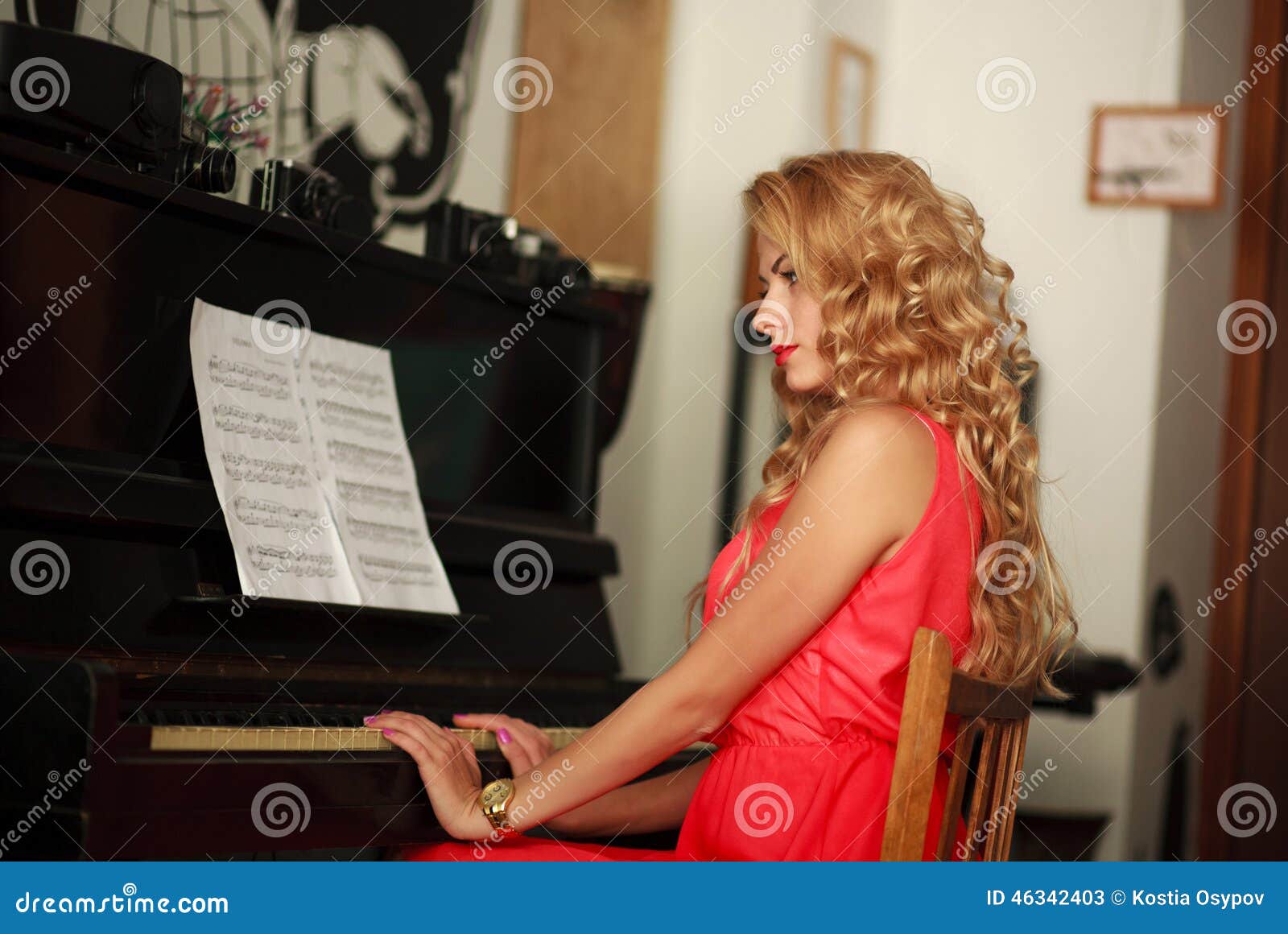 Beautiful Young Woman Sitting at the Piano in the Room Stock Image