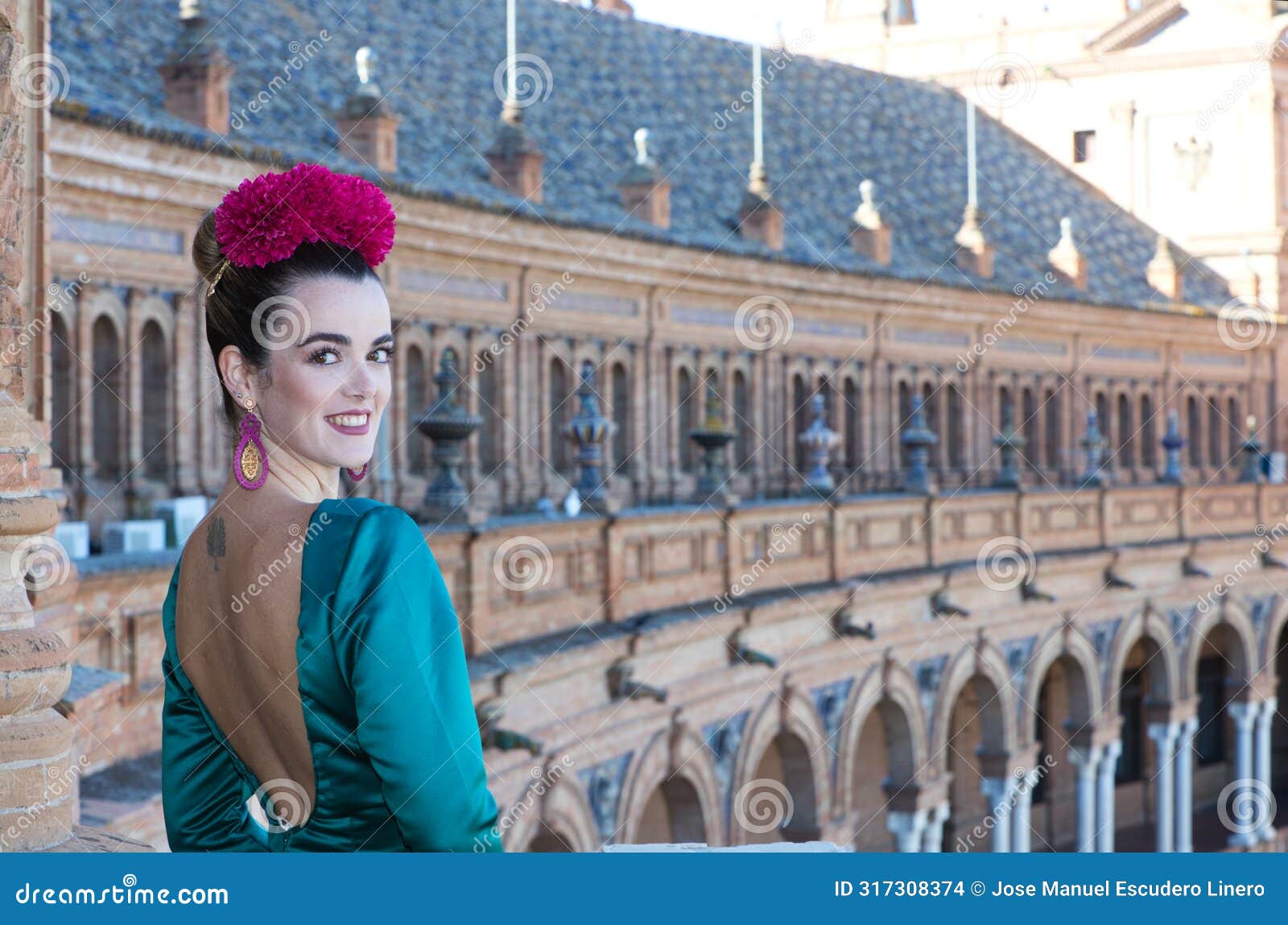 beautiful young woman with typical green frilly dress and dancing flamenco in plaza de espana in sevilla, andalusia, she is on a