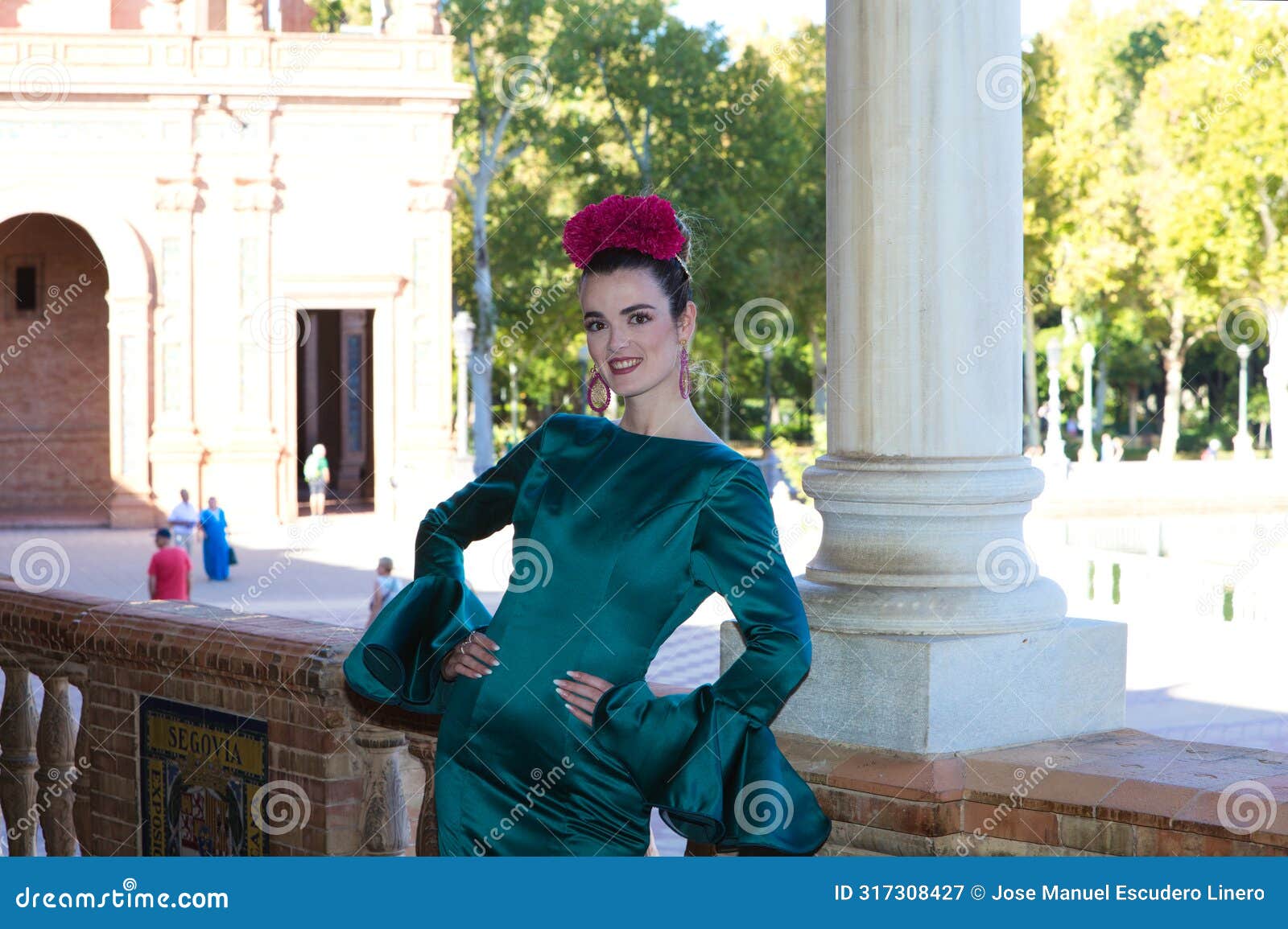 beautiful young woman with typical green frilly dress and dancing flamenco in plaza de espana in sevilla, andalusia, she is on a