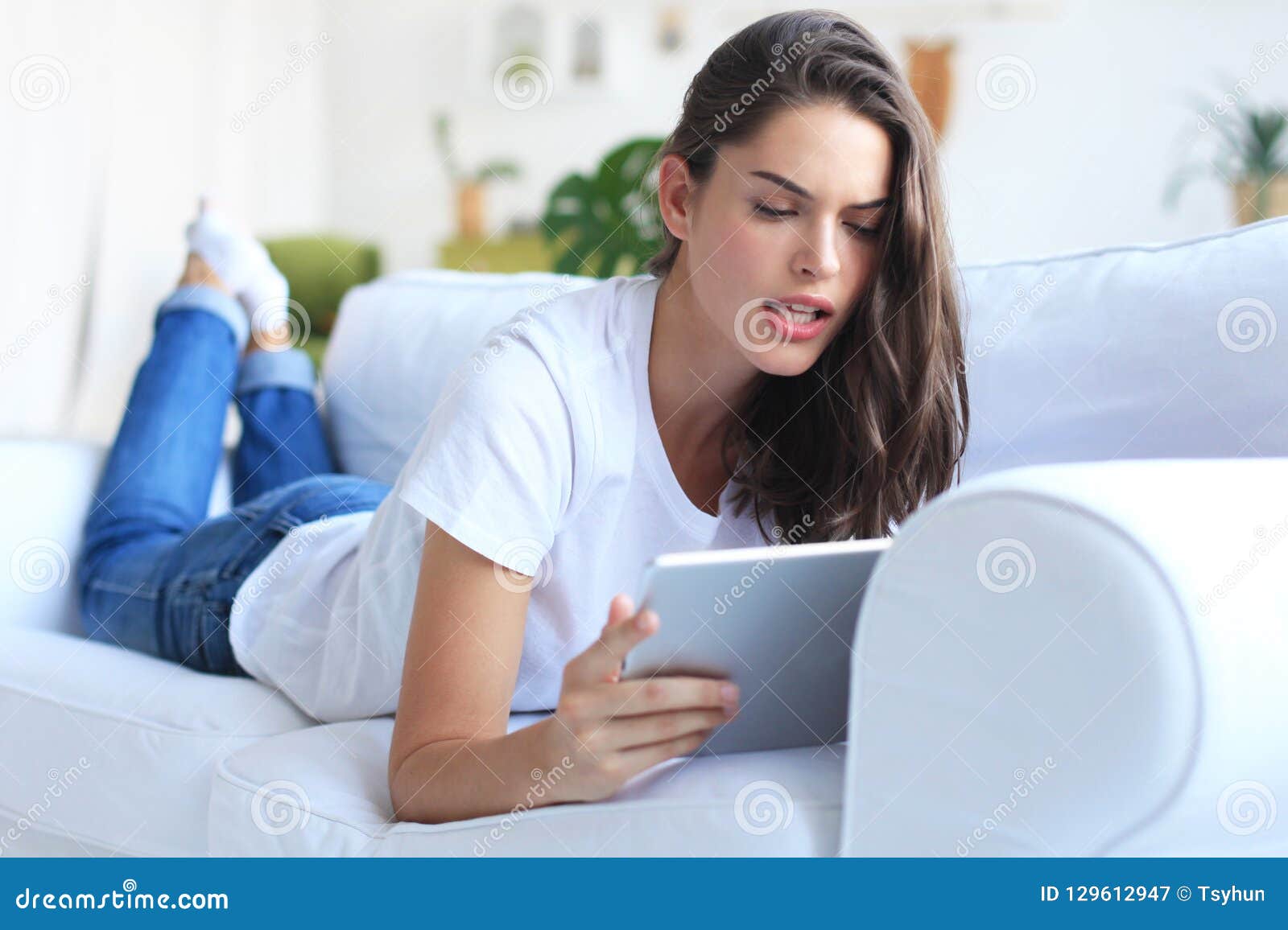 Beautiful Young Woman Using Tablet Sitting on Sofa at Home at Living ...