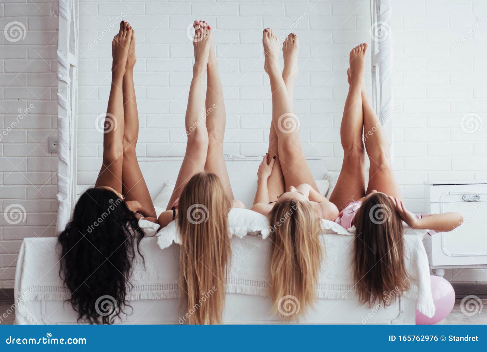 beautiful youth. four young women with good body  lying on the bed with their legs up