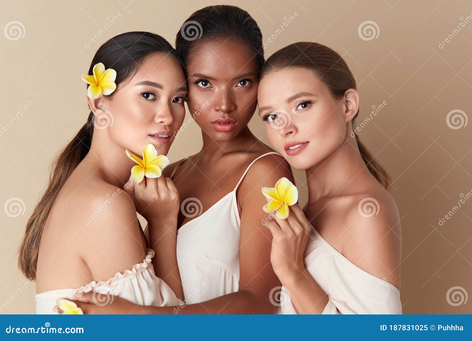 beauty. diverse group of women portrait. tender models of different ethnicity posing with tropical flowers in hands.