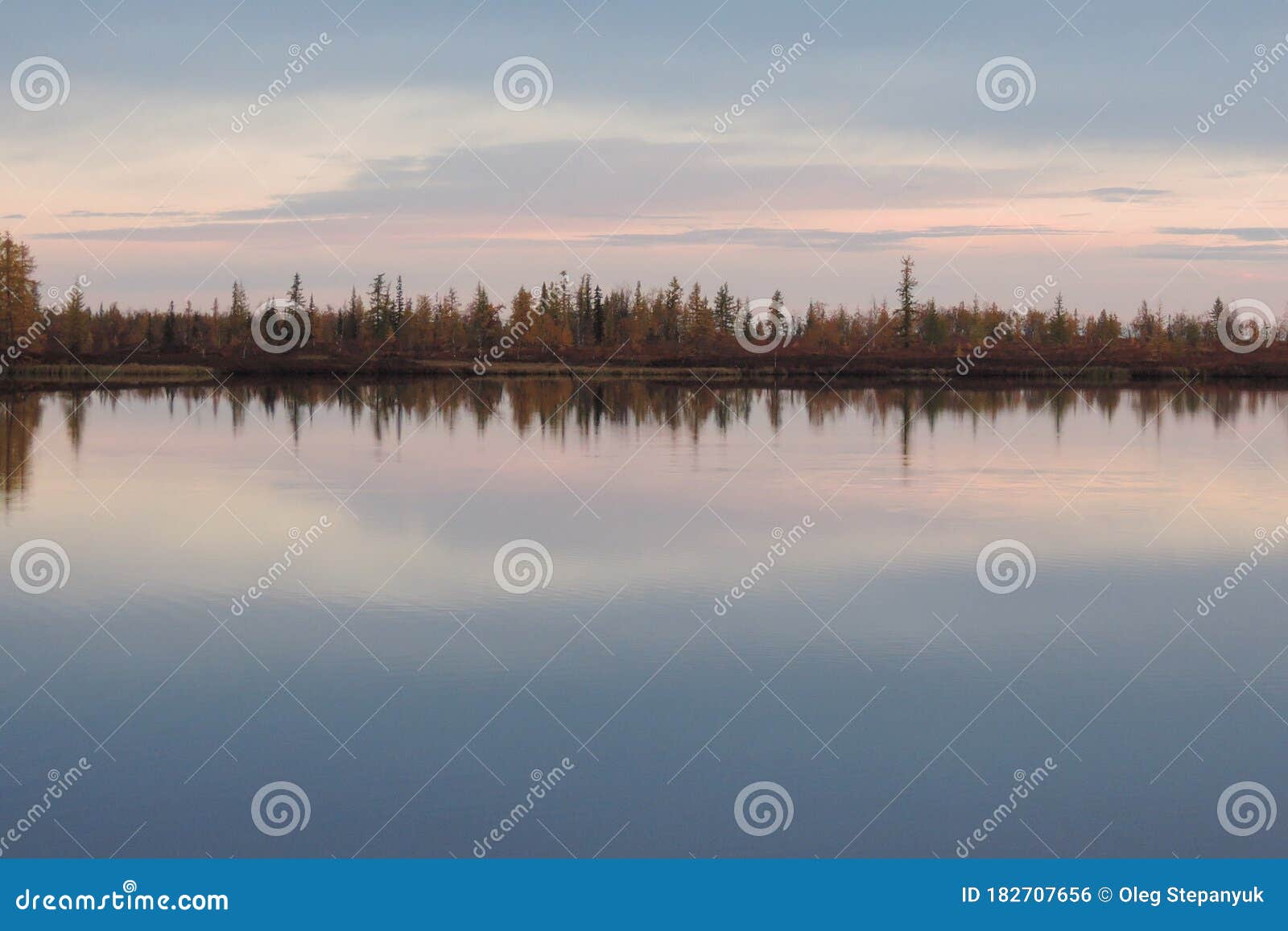 in the calm water of the arctic lake, as in a mirror, the sunset is reflected. september evening in the autumn tundra.