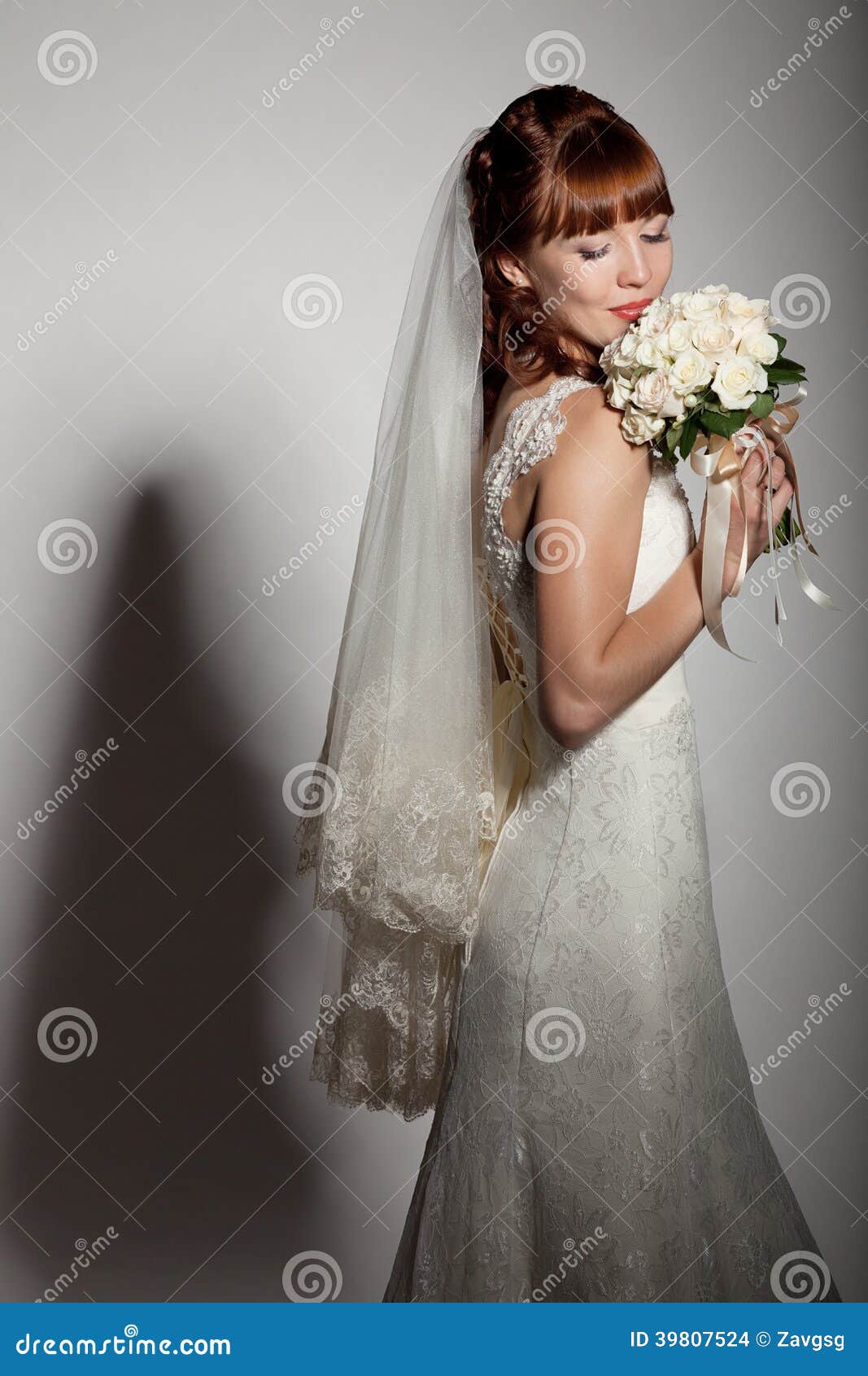 a beautyful bride looks down at her bouquet from roses.