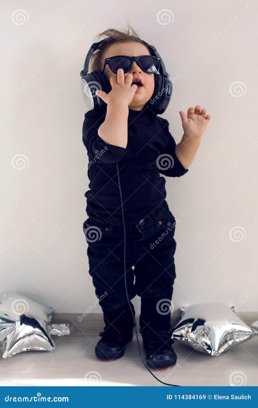 Bebé De Un Año En Ropa Negra Que Escucha La Música Imagen - Imagen de equipo, ojos: 114384169
