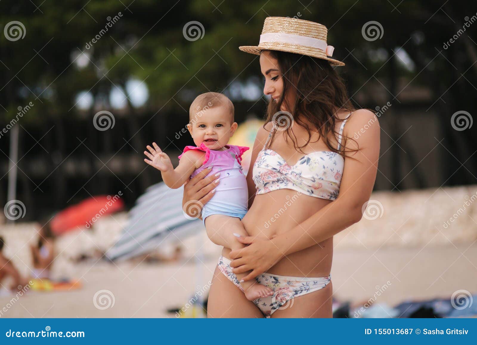 Turista Marinero Cumplimiento a Bebé Del Control De La Madre a Mano En La Playa Mamá E Hija En Traje De Baño  Sombrero Hermoso Imagen de archivo - Imagen de arena, fondo: 155013687