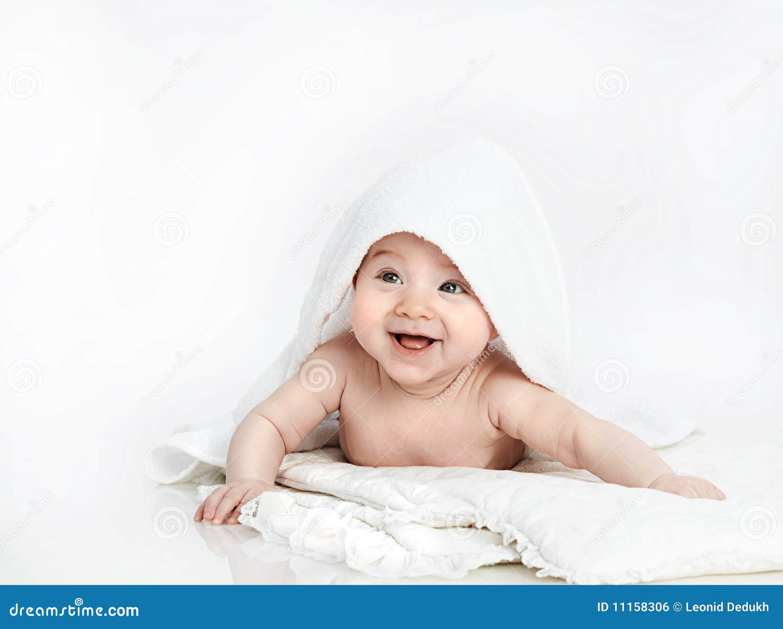 Bebé del pequeño niño que miente bajo sonrisa de la toalla