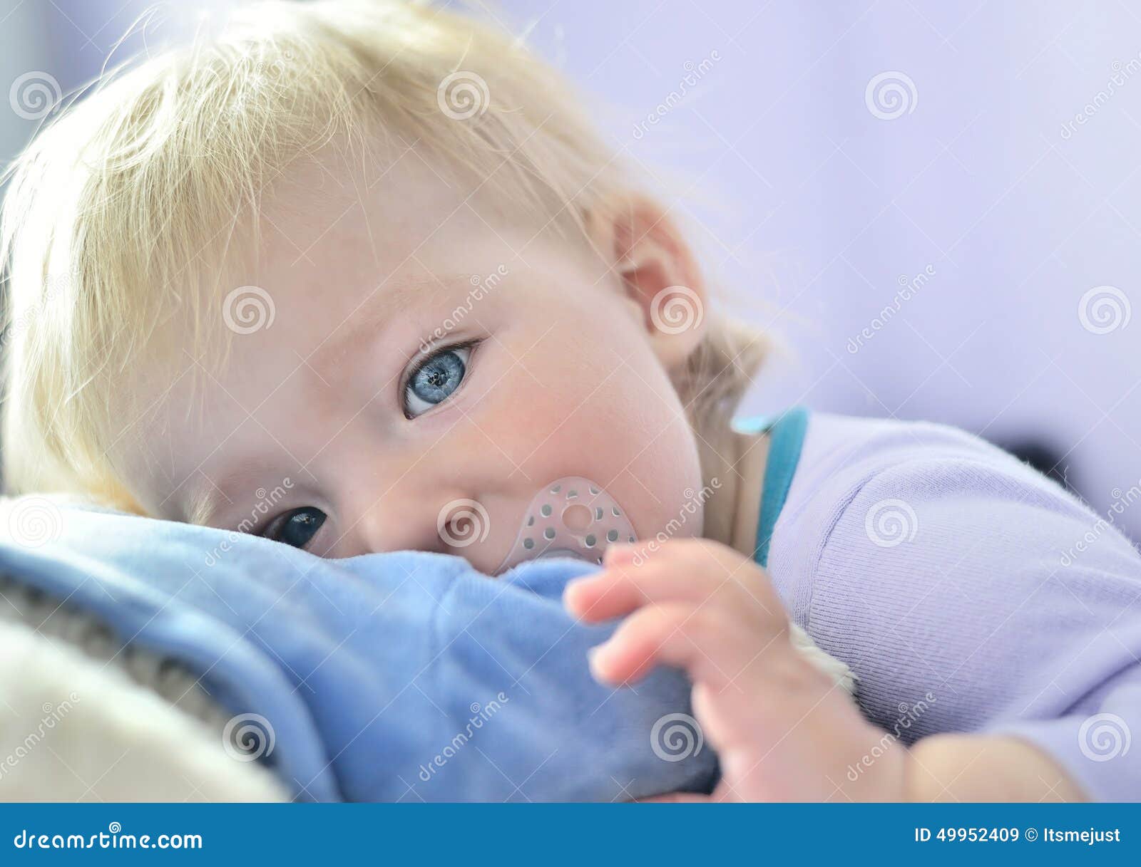 Bebé lindo con los ojos azules que abrazan una mascota