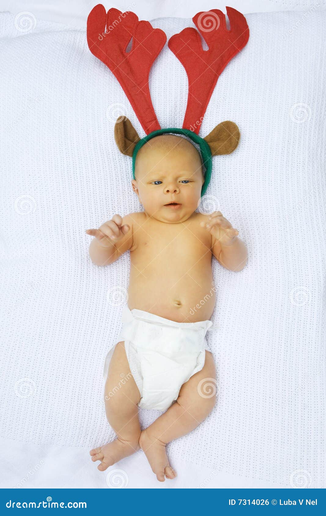 Bebê do Natal. Bebé pequeno no tecido descartável no cobertor do algodão com o chapéu do Natal da rena