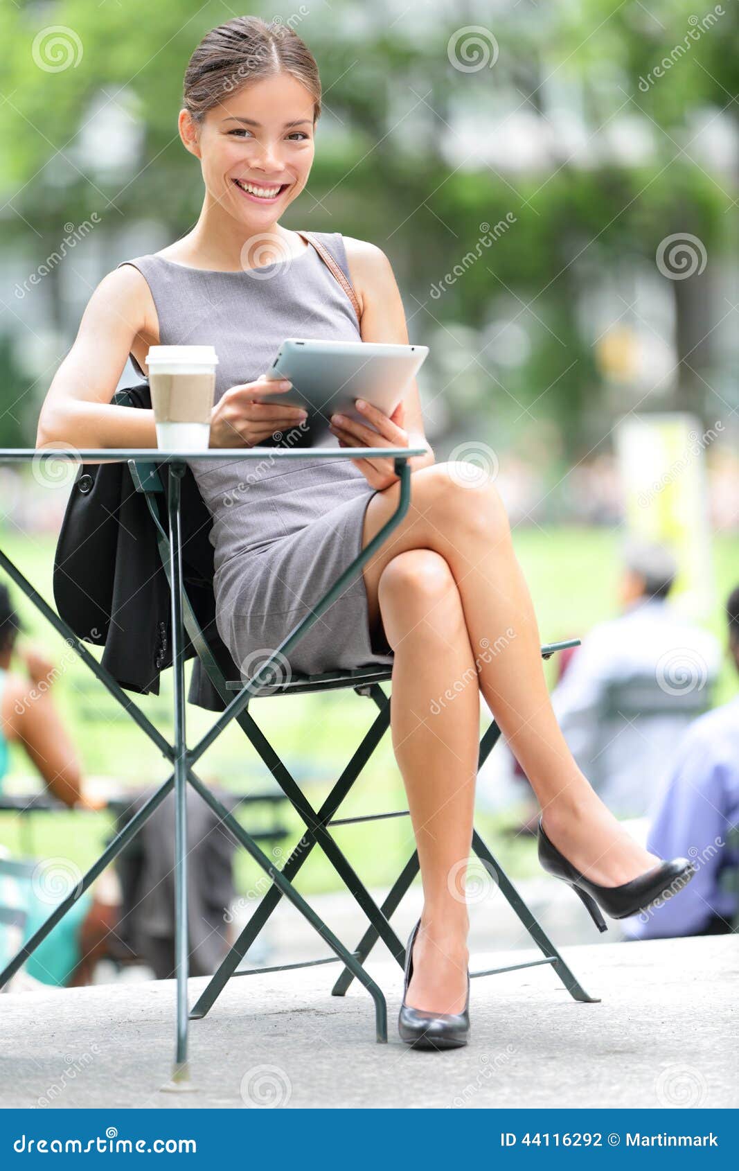 Bedrijfs vrouw die tablet op onderbreking gebruikt. Bedrijfsvrouw die tablet op koffiepauze in stadspark gebruiken Jonge professionele onderneemsterzitting bij lijst bij koffie Foto van Bryant Park, de Stad van New York, de V