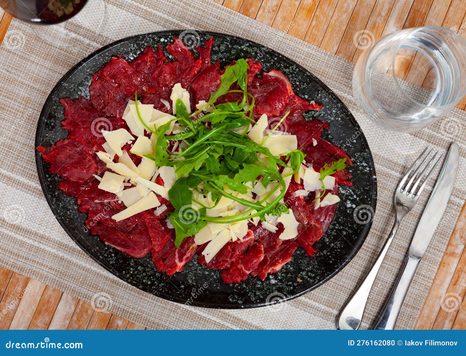 Beef Carpaccio with Arugula Slices of Cheese on Table Stock Photo