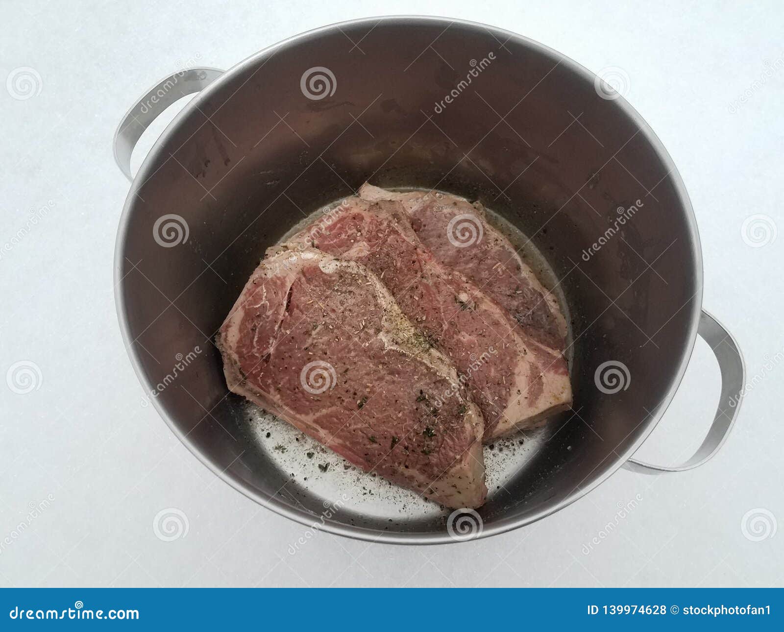 Beef Steak with Seasoning and Liquid in Metal Pot on Snow Stock Photo