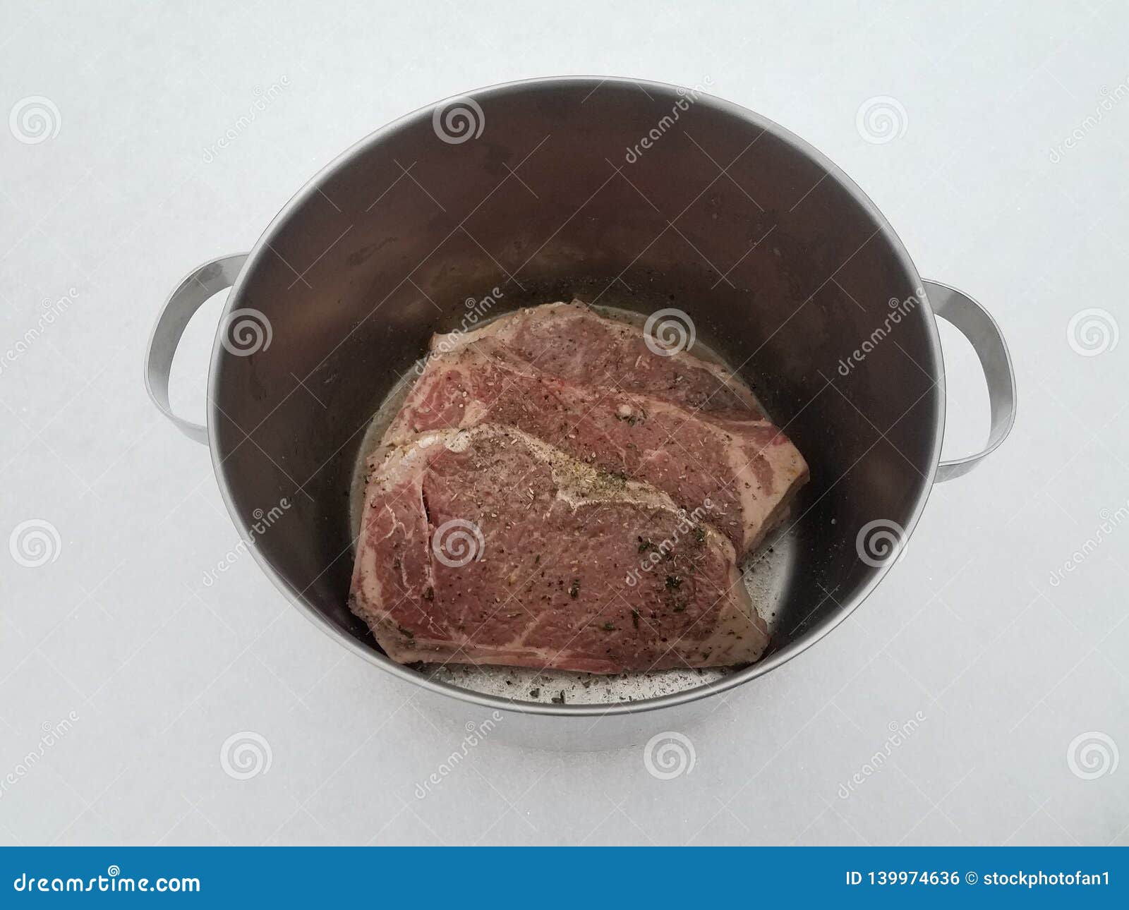 Beef Steak with Seasoning and Liquid in Metal Pot on Snow Stock Photo