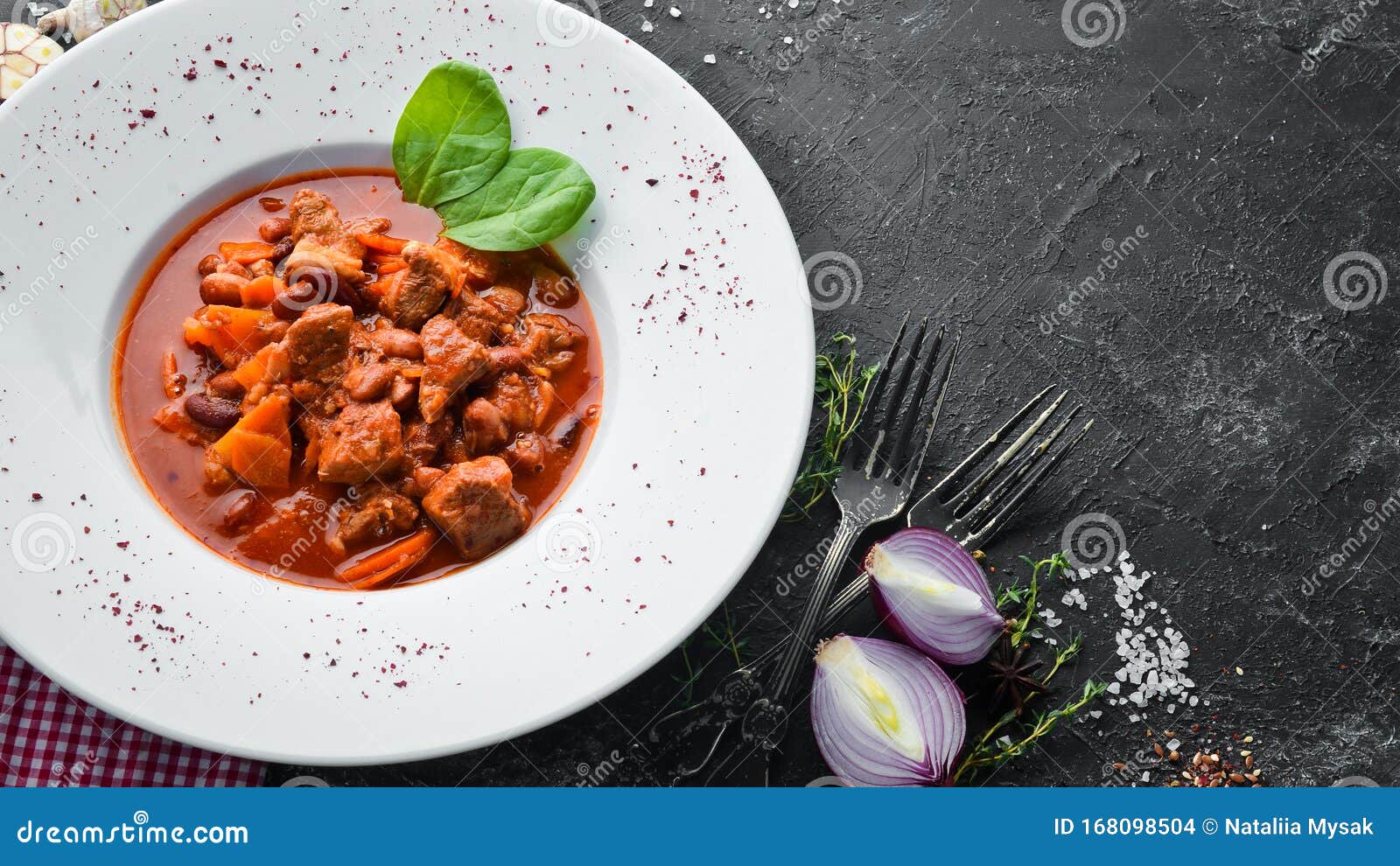 beef stew with beans and vegetables in a tomato sauce on a plate. top view.