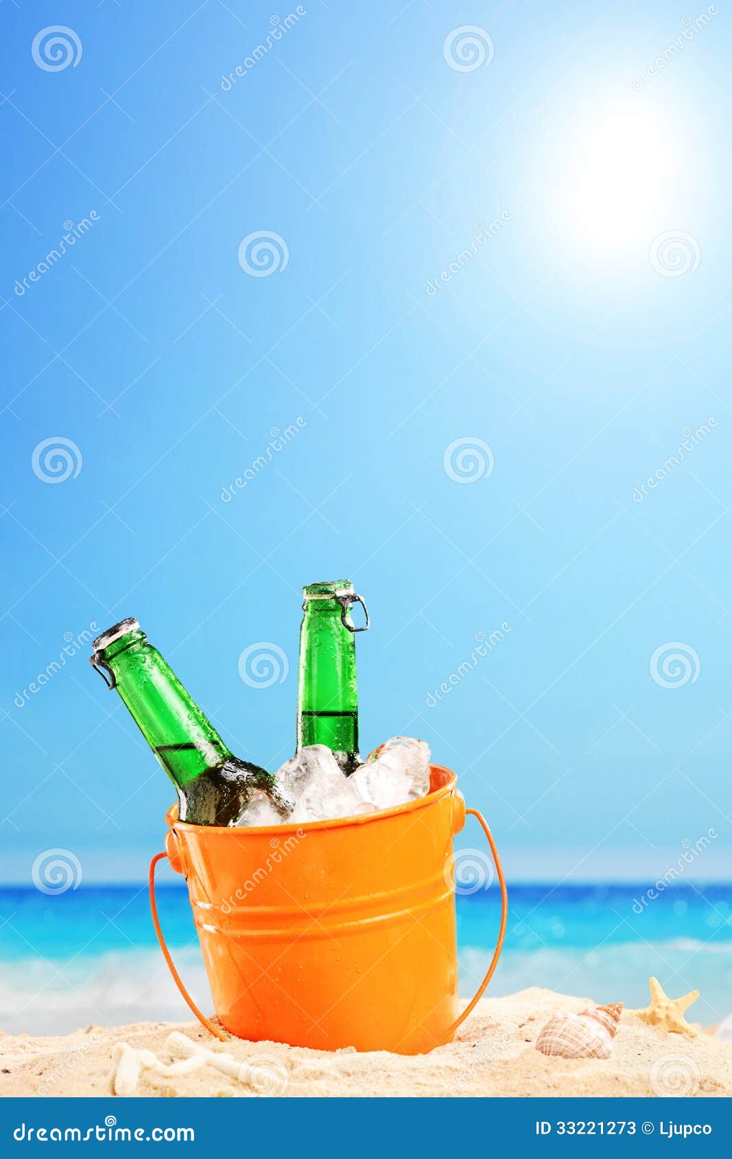 Beer Bottles in a Bucket of Ice in the Sand on a Beach Stock Image