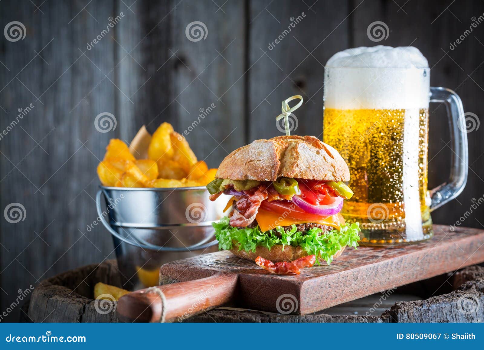 Beer and fresh hamburger made of beef, cheese and vegetables on wooden background