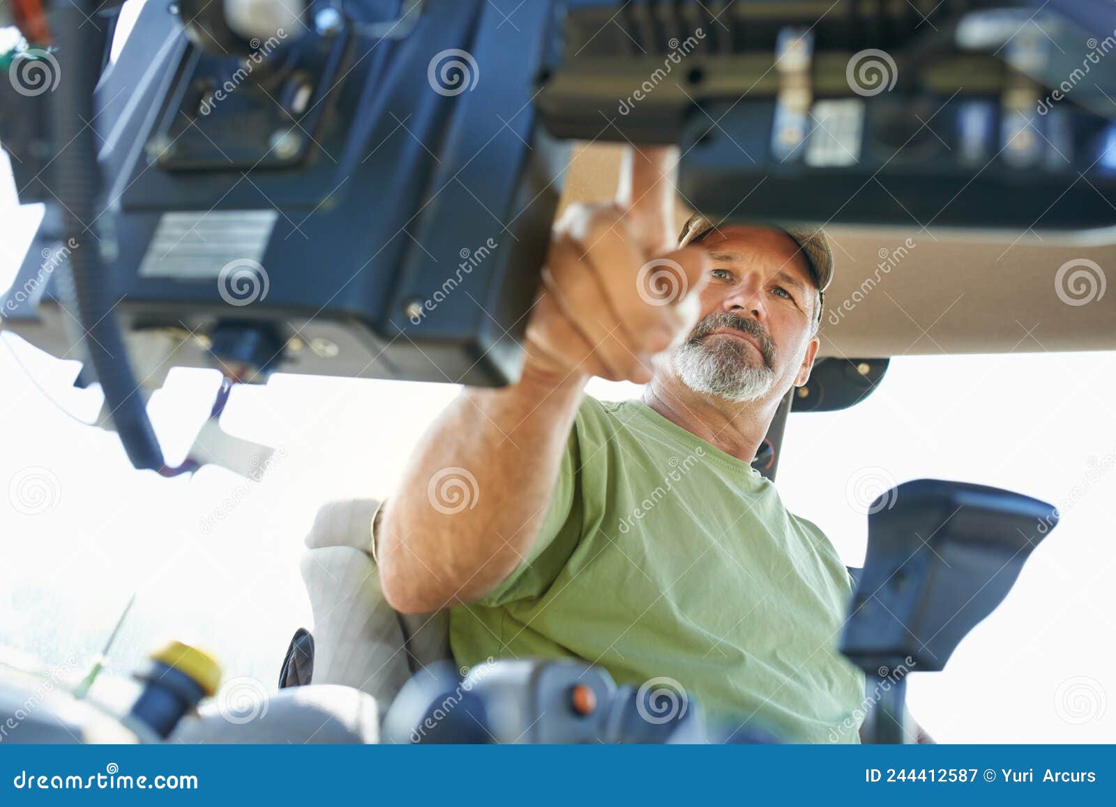 the beginning of the farming day. shot of a farmer working inside the cab of a modern tractor.