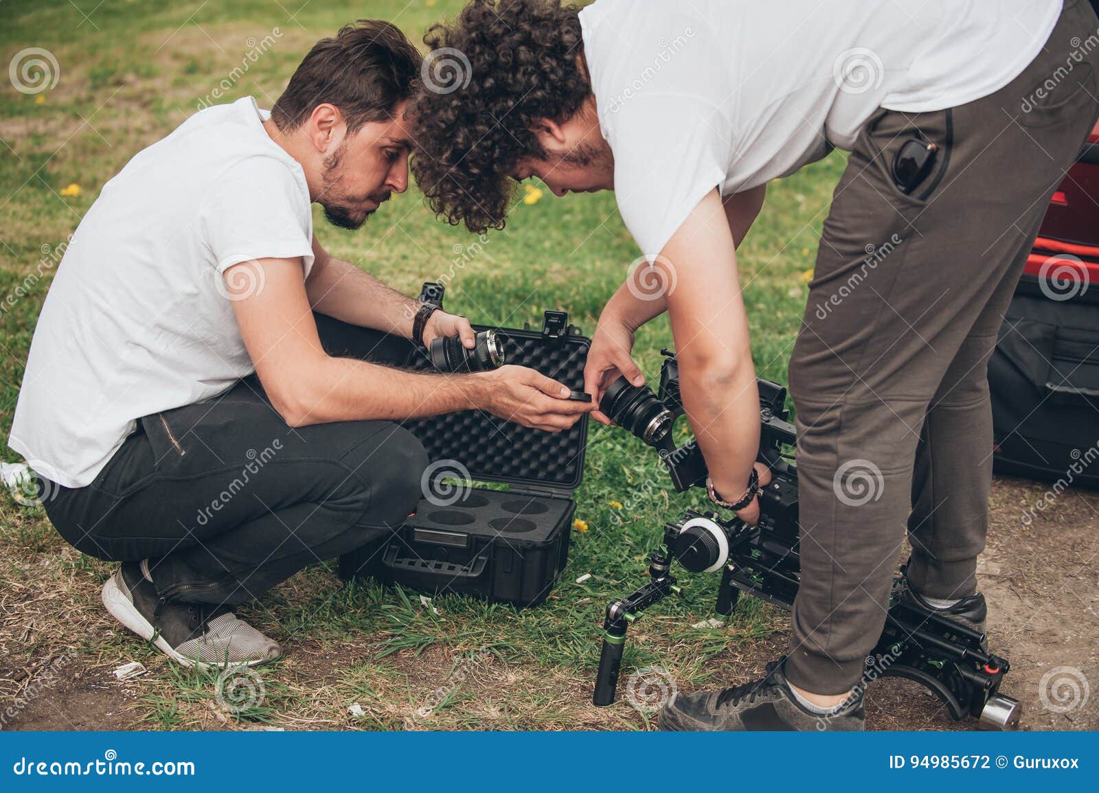 Behind the Scene. Cameraman and Assistant Changes Lens on Camera Stock