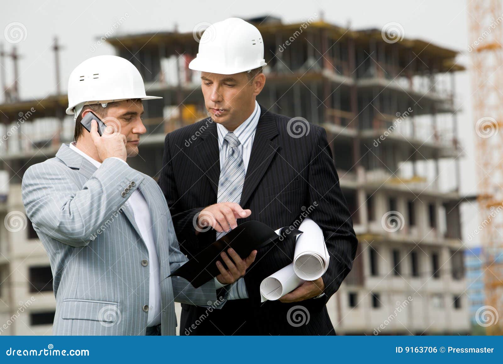 Bei der Sitzung. Portrait von zwei Ingenieuren, die draußen an der Baustelle zusammenwirken