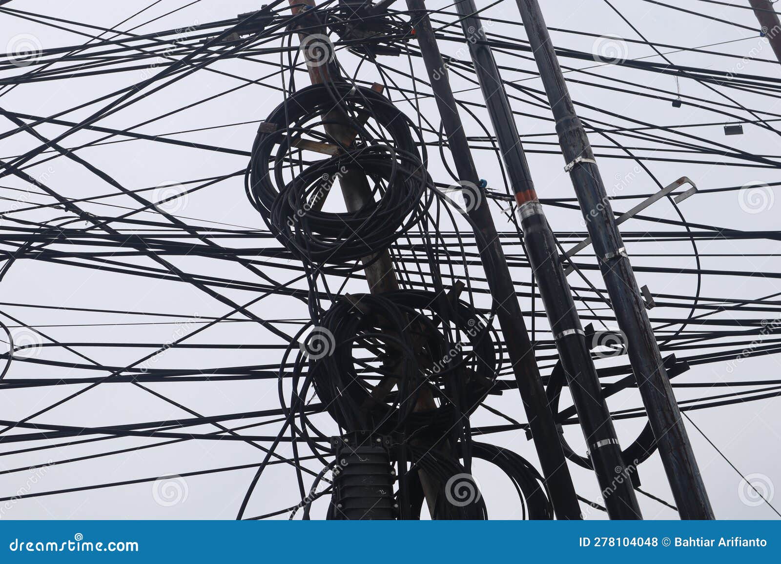 Untidy Electricity Cables Over Head With Bright Sky In The Background