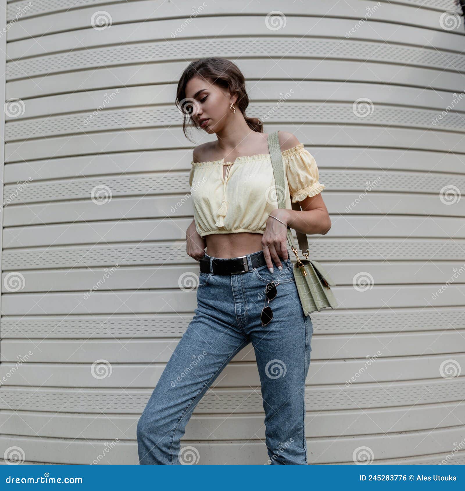 https://thumbs.dreamstime.com/z/bela-mulher-coroa-elegante-em-uma-blusa-amarela-na-moda-jeans-azul-casual-com-bolsa-verde-numa-de-245283776.jpg