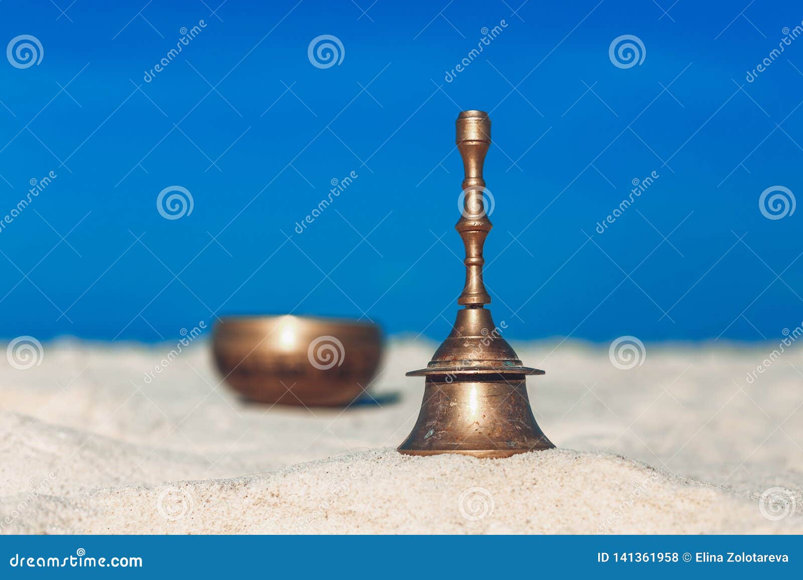 Bell and Singing Bowl on the Sand. Musical Instruments on the Beach