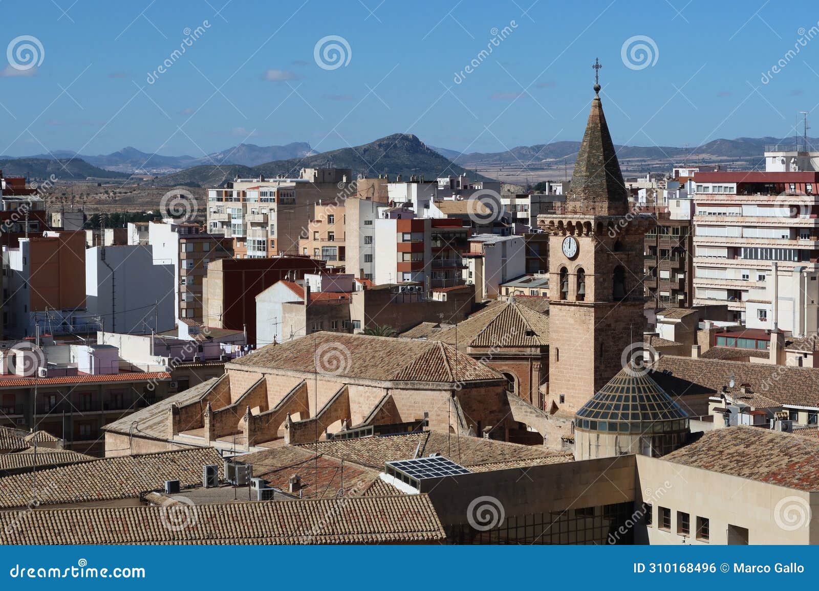 bell tower of the church of santiago apostol with mountains in the background. villena, alicante, spain