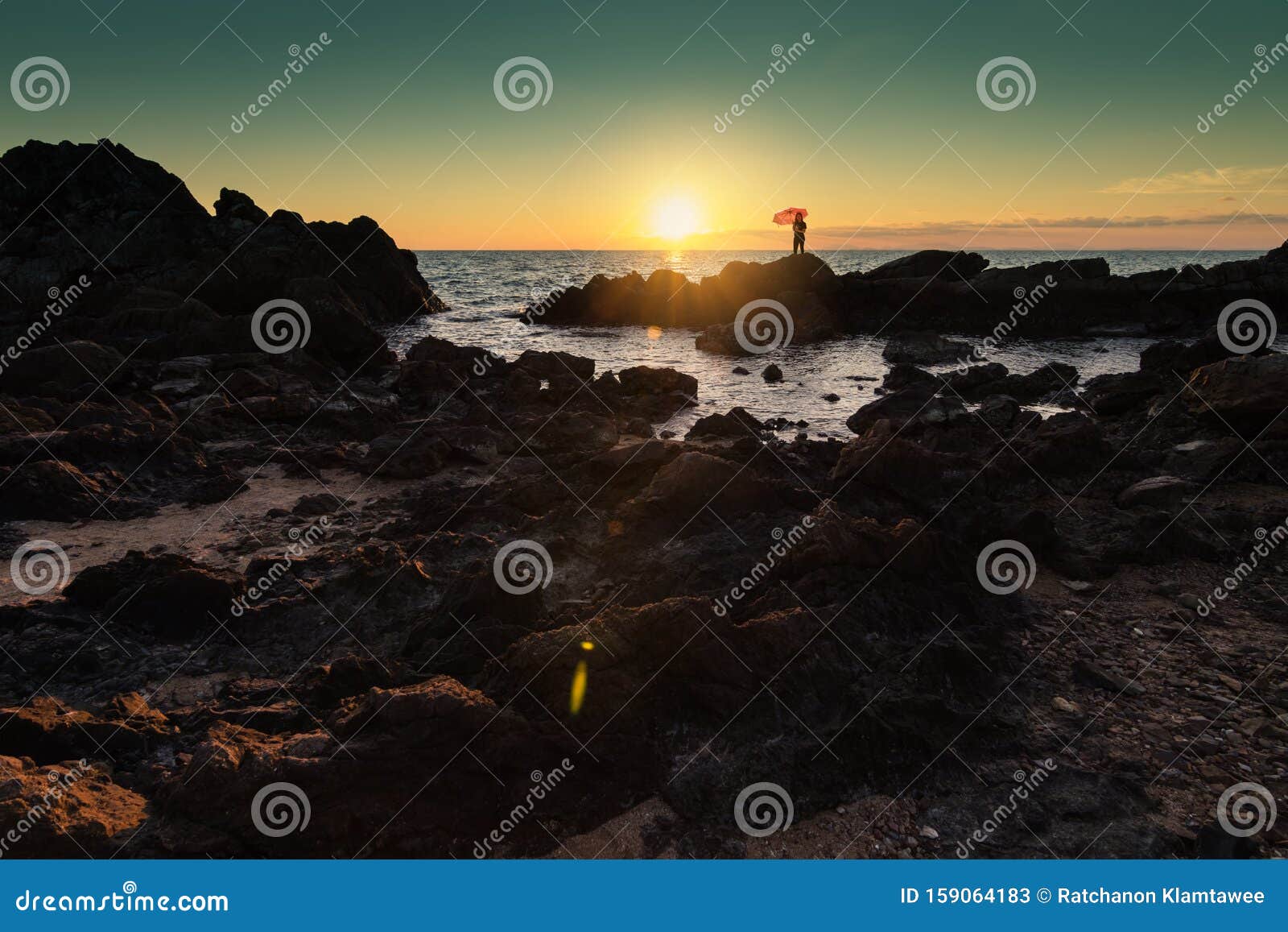 Bellissima una donna che tiene in mano un ombrello e si trova su un litorale roccioso.