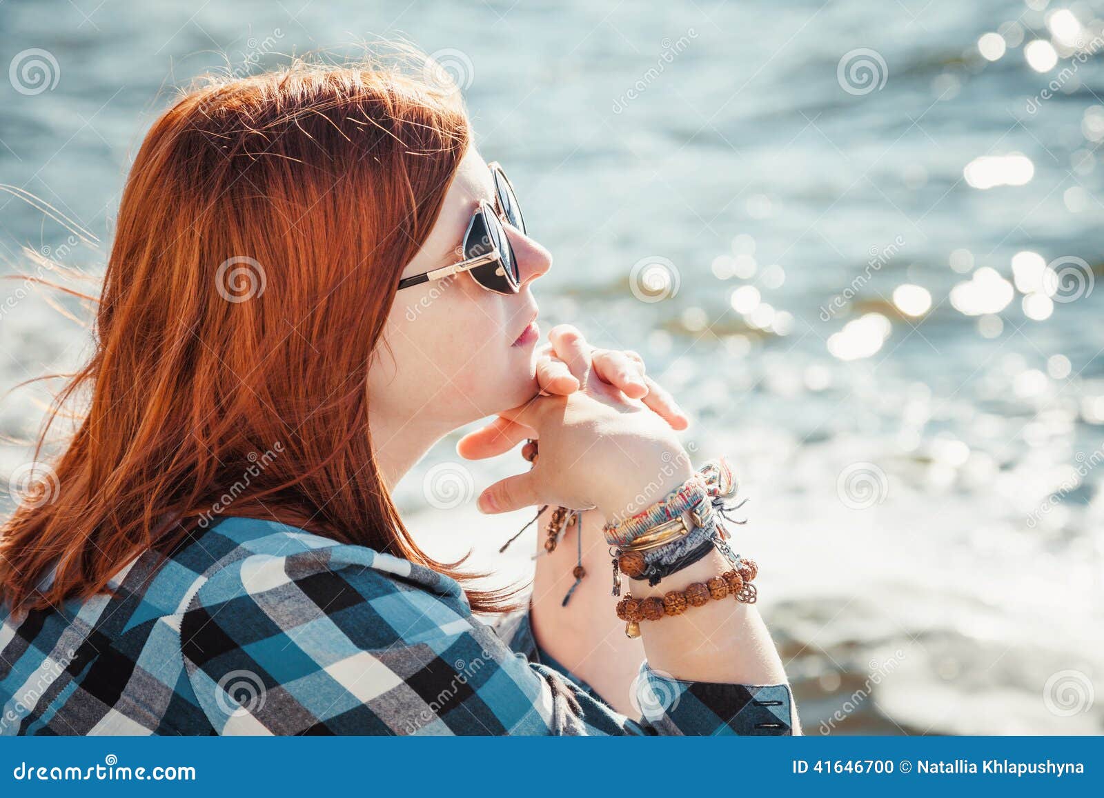 Bella giovane donna rossa dei capelli in occhiali da sole sulla spiaggia. Bella giovane donna rossa dei capelli in occhiali da sole che si siedono sulla spiaggia