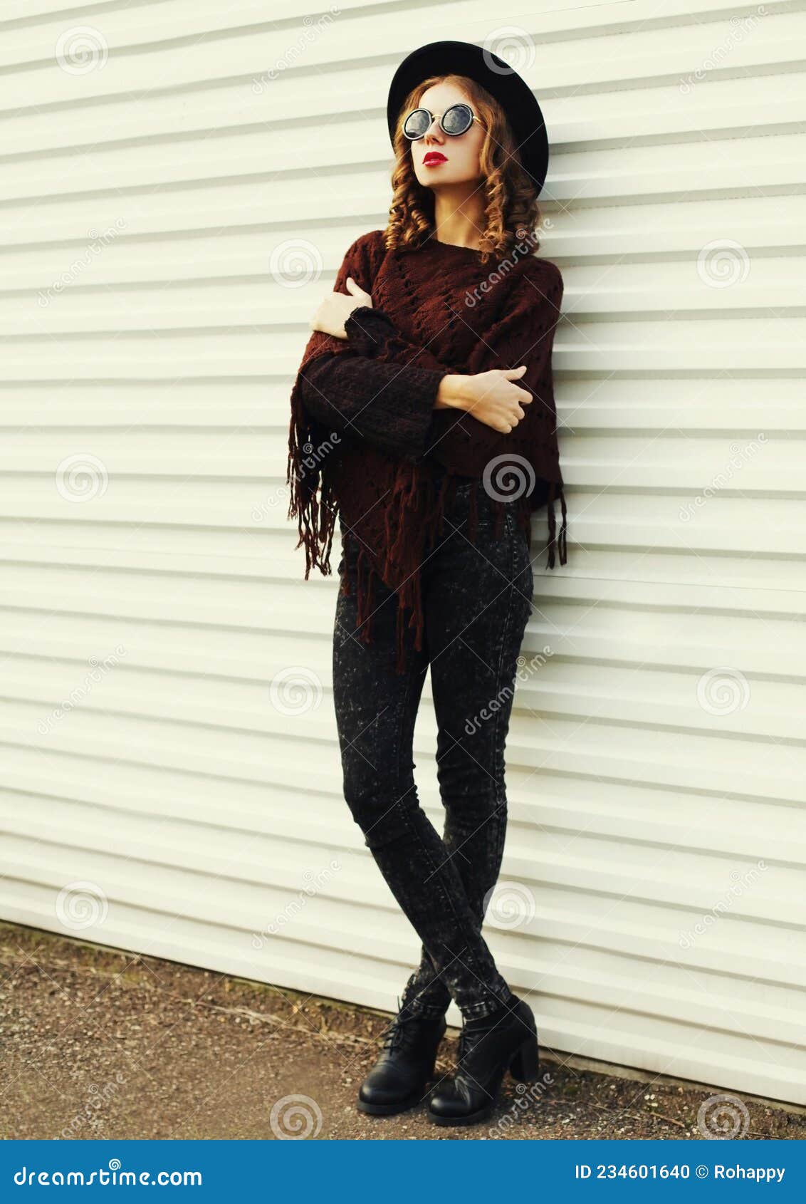 Mujer joven y bonita rubia rizada con poncho en el parque de