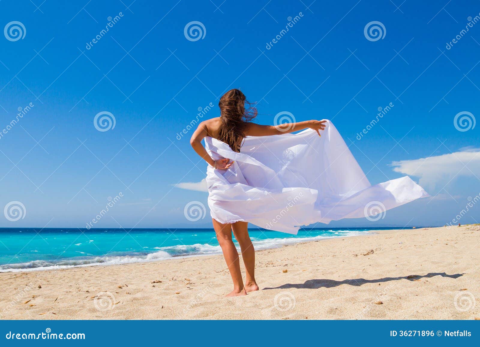 Bella ragazza con tessuto bianco sulla spiaggia. Viaggio e vacanza. Concetto di libertà.