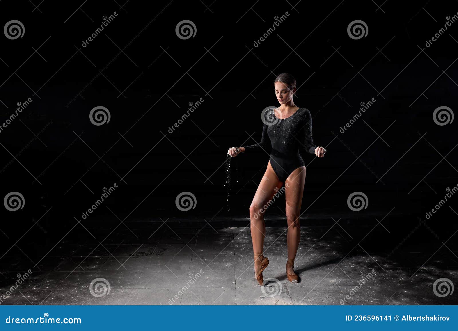 Danseuse de ballet en body noir saute haut et danse avec de la farine sur la