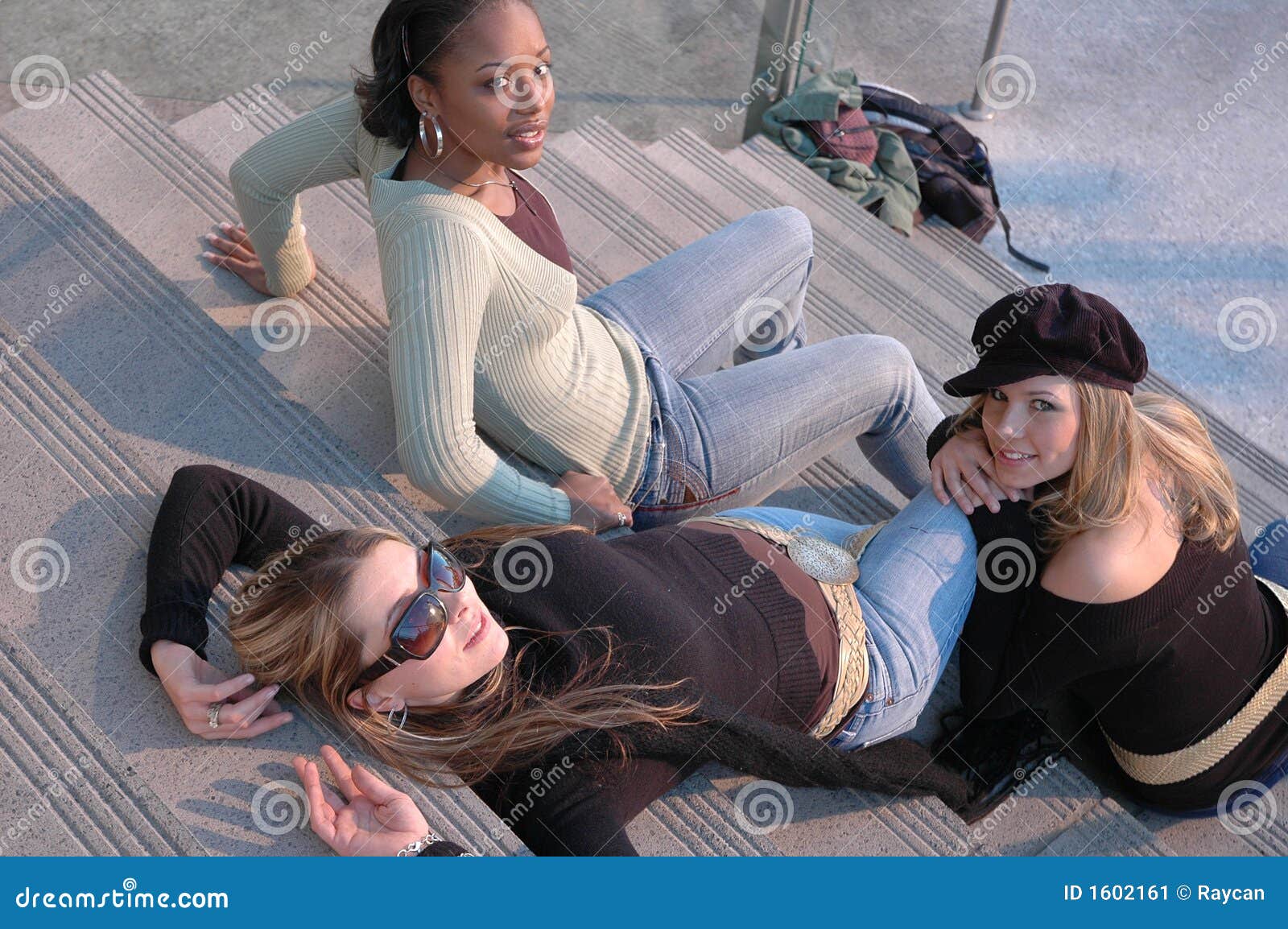 Belle donne. Tre amici che appendono fuori in una zona del centro commerciale. Tre modelli di modo che si siedono su alcuni punti all'esterno.