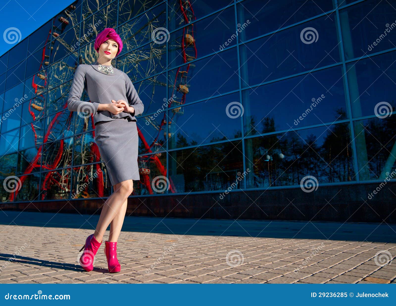 Façonnez la photo d'une belle femme devant une construction avec la réflexion de la roue de Ferris à l'heure d'été