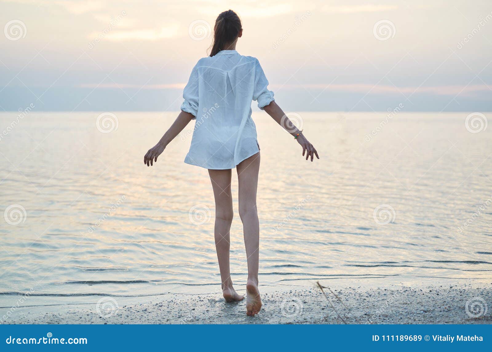 Belle Femme Sexuelle Dans La Chemise Et Le Bikini Blancs Marchant Sur La Plage Contre La Mer Et
