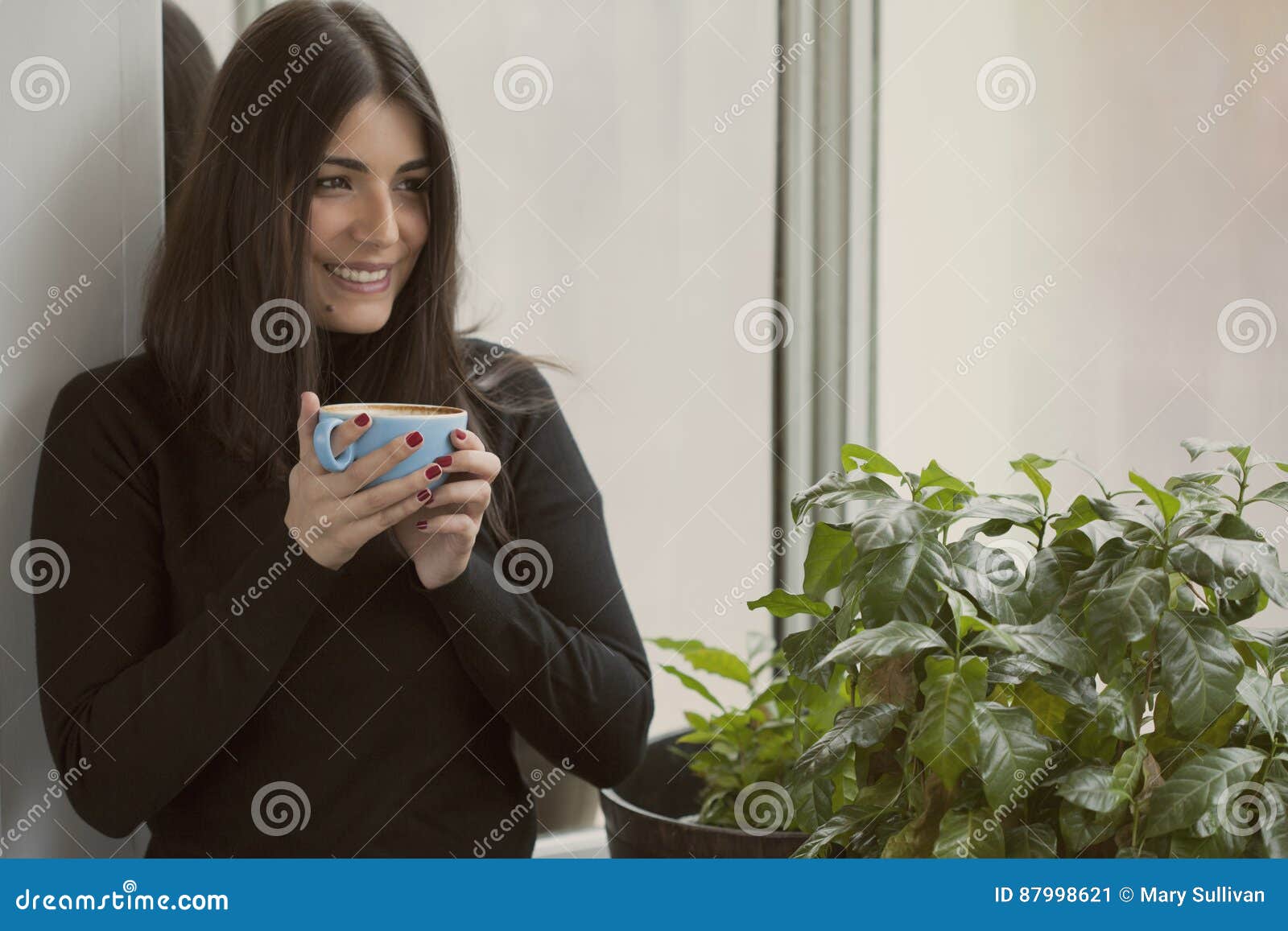 Belle femme tenant le café avec le sourire rouge de clous. Belle femme de brune tenant un café souriant avec les clous rouges