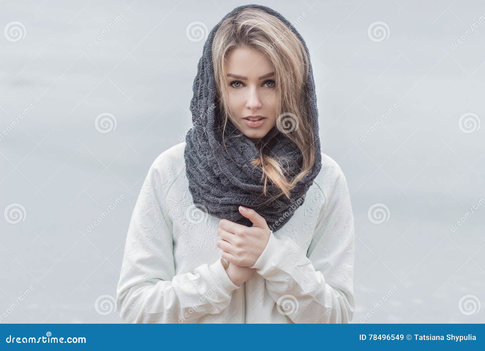 Belle fille avec de belles lèvres dans une veste blanche avec une écharpe chaude sur la tête en temps froid
