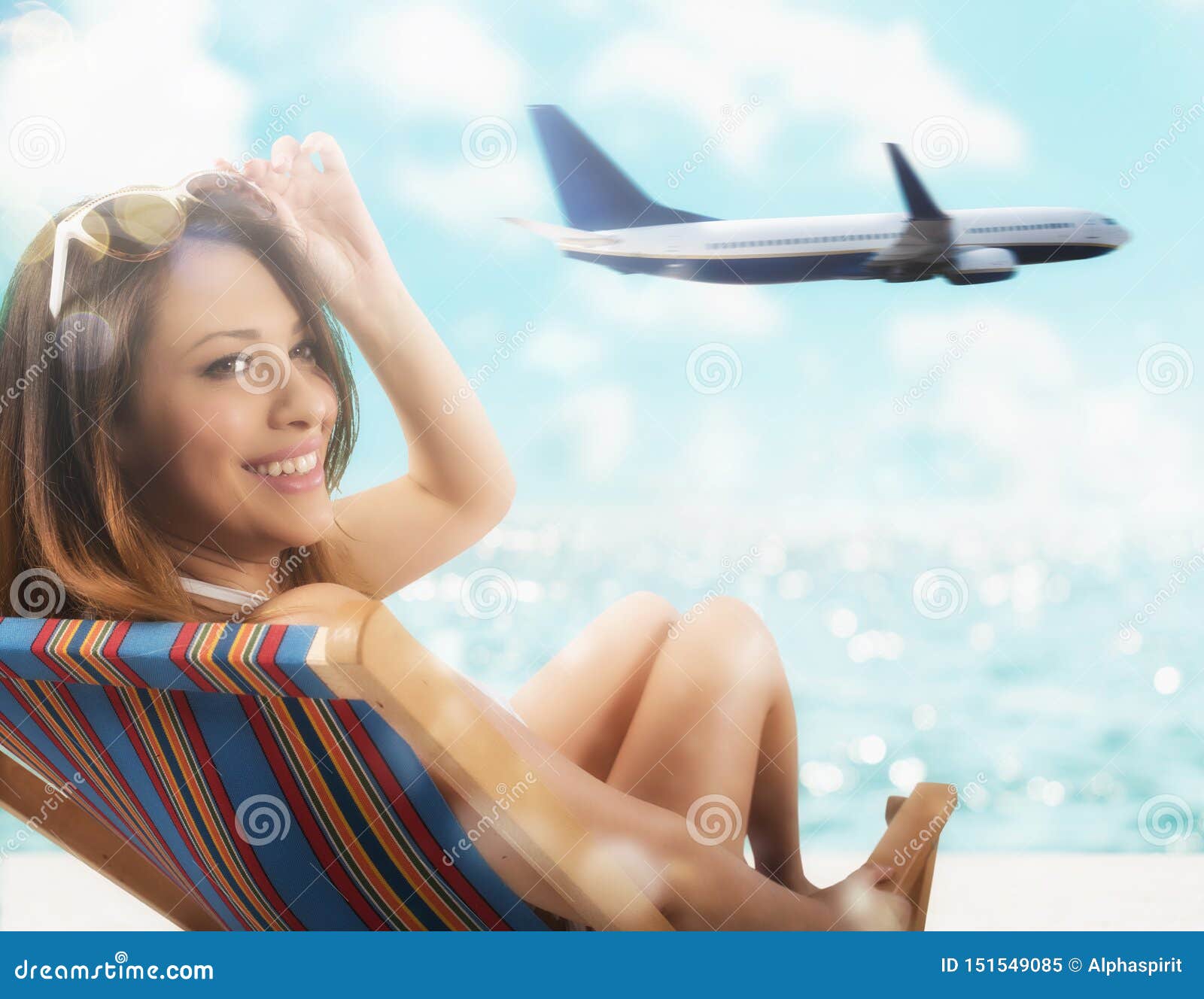 Belle fille s'asseyant sur une chaise de plate-forme à la plage au coucher du soleil avec l'avion sur le fond. Se reposer de touristes à la plage devant la mer avec l'avion sur le fond