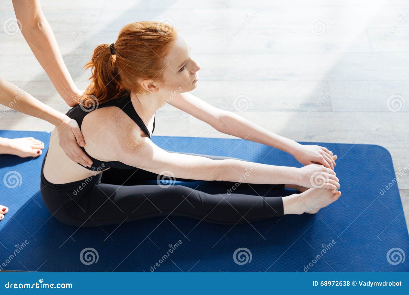 Vue supérieure de la belle jeune femme rousse faisant le yoga avec l'entraîneur personnel dans le studio