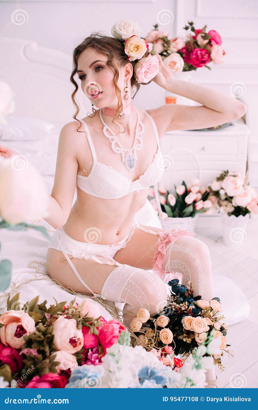 Belle jeune femme sexy, lingerie blanche de port, pièce décorée des fleurs Maquillage parfait Mode de beauté cils Studi. Belle jeune femme, cheveux décorés des fleurs Maquillage parfait Mode de beauté cils Tir retouché par studio L'atmosphère tendre et douce, couleurs en pastel