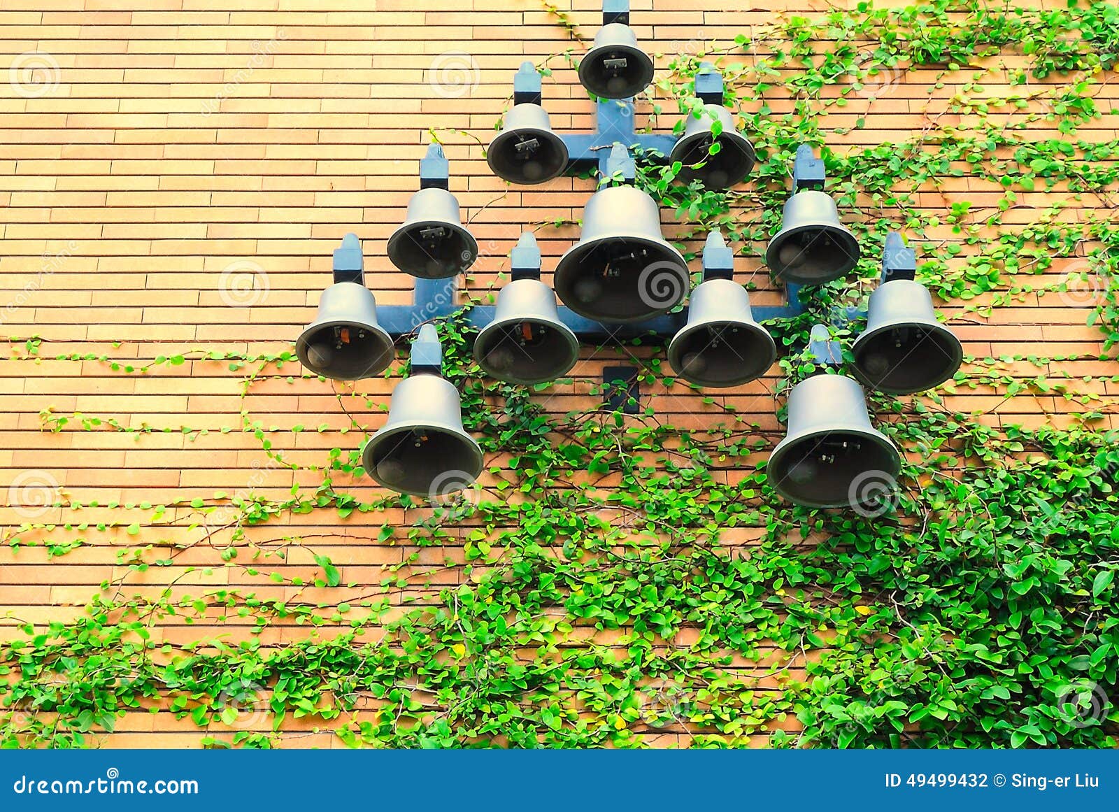 Bells are Hanged on the Wall Climbed by Plants. Stock Photo Image of
